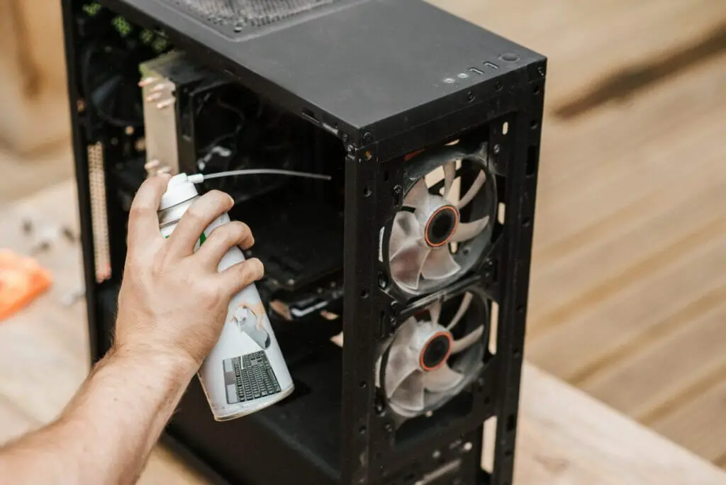 A person cleaning the PC Compartment with rust-cleaning spray